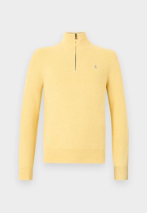 Gul langermet strikkegenser med kvartglidelås i kragen og liten brodert logo på venstre bryst.