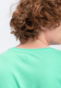 T-shirt in cotone verde menta con scollo rotondo e maniche corte. Presenta un piccolo design ricamato a forma di ciliegia nella zona del collo sul retro.