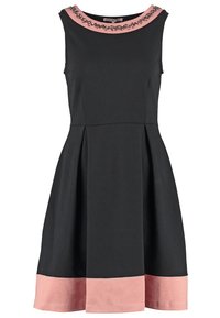 Svart ärmlös klänning med en rosa krage och fåll. Har dekorativa utsmyckningar på halsringningen och en utställd kjol.