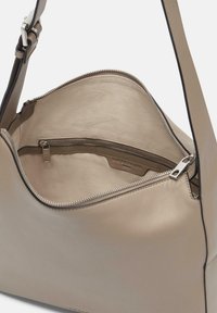 Beżowa skórzana torebka z zamkiem błyskawicznym; posiada gładkie wnętrze, odpinany pasek oraz wewnętrzną kieszeń na bezpieczne przechowywanie.