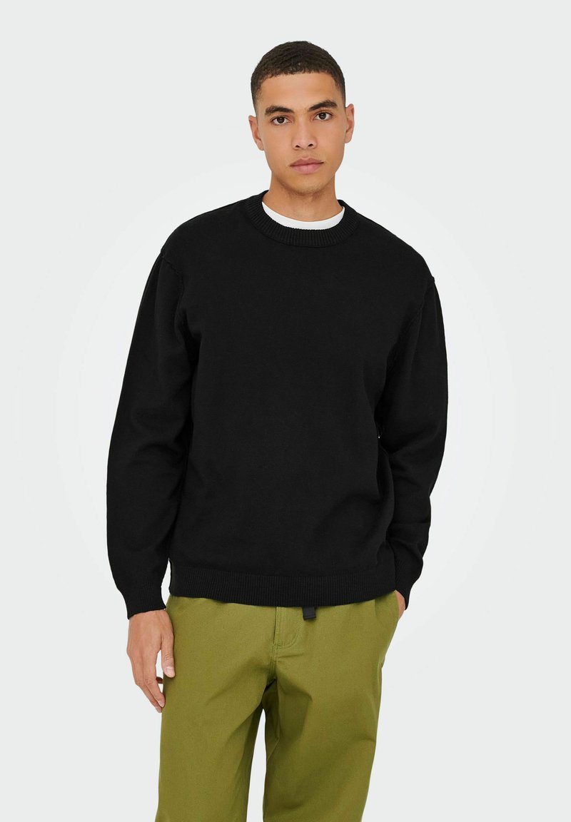 Sweatshirt noir à col rond avec des poignets et un ourlet côtelés, fabriqué dans un matériau doux. Associé à un pantalon vert olive, au fit décontracté.