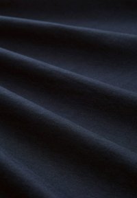 Tissu bleu marine avec une texture lisse, présentant de douces plis et un motif de tissage uniforme. Matériau léger avec un léger éclat.