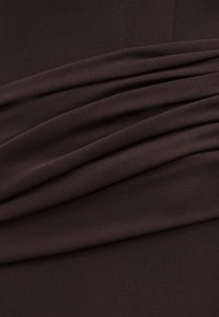 Σκούρο καφέ ύφασμα με απαλά, οριζόντια πτυχώματα και λεπτή, λεία υφή ορατή σε όλη την επιφάνεια.