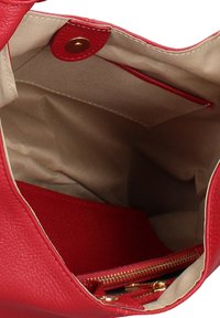 Rode leren handtas met een ruime binnenkant, bekleed met beige stof, een ritsvak en een drukknoopsluiting.