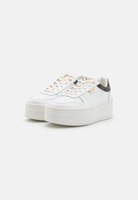 Sneakers bianchi in pelle con suola platform bianca spessa, dettagli dorati e un motivo scuro sul tallone. Design con lacci e forature.