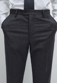 Mörkgråskräddade byxor i ett lent, strukturerat tyg, med knappstängning, bältesöglor och sido- fickor.