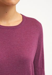 Sweter dzianinowy w głębokim fioletowym kolorze, z okrągłym dekoltem i długimi rękawami, charakteryzujący się miękką teksturą i równym ściegiem.