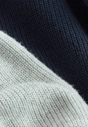 Zwei überlappende Strickstoffe: einer in hellgrau, der andere in dunkelmarineblau. Beide haben ein strukturiertes, geripptes Design und weiche, flauschige Oberflächen.