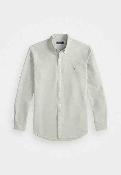 Ανοιχτό γκρι πουκάμισο με μακριά μανίκια, φτιαγμένο από μαλακό ύφασμα, με μια μικρή κεντητή λογότυπο στο στήθος και κλασικό γιακά.