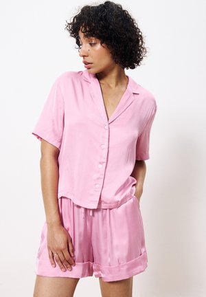 Roze satin knoopshirt met korte mouwen en bijpassende shorts, met een relaxte pasvorm en een gladde textuur. Geen opmerkelijke patronen of hardware.