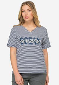 T-shirta z dekoltem w serek i krótkim rękawem w granatowo-białe paski, z dużą grafiką "OCEAN" w kontrastowych kolorach na środku.