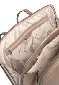 Beige leren tas interieur met een soepele textuur, voorzien van een ritsvak en een lichtgekleurde voering met een herhaald "HEXAGONA" tekstpatroon.