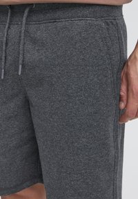 Grå bomuldsblandingsshorts med blød tekstur og elastisk taljebånd. Har syede sidesømme og justerbare snore.