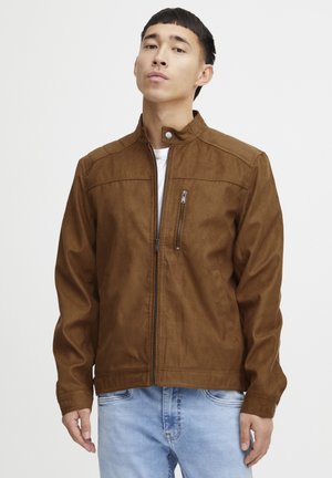 Veste en daim marron avec un col haut, fermeture éclair à l'avant et une poche poitrine. Présente une texture lisse et une silhouette ajustée.