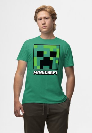 Zelené bavlněné tričko s velkým černým a zeleným pixelovaným designem obličeje Creepera a textem "MINECRAFT" v bílé barvě pod ním.
