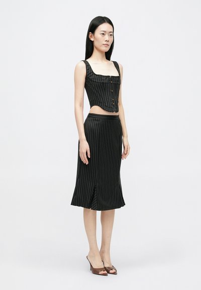 Top corto negro a rayas con escote cuadrado y botones, combinado con una falda midi negra que presenta un dobladillo acampanado y acentos de abertura lateral.