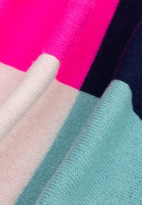 Close-up van gebreide zachte stof met kleurvlakken in felroze, marineblauw, lichtroze en lichtblauw, met zichtbare textuur en plooien.