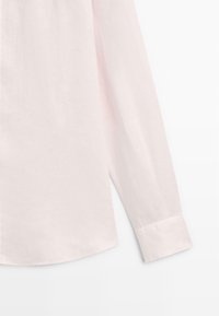 Lichtroze lange mouwen shirt van linnen. Heeft een ronde zoom en een gebloemde manchet. De stof heeft een gladde, licht gestructureerde uitstraling.