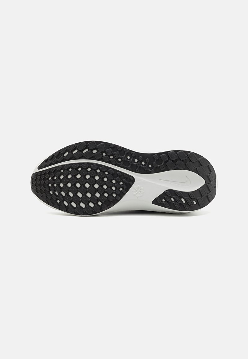 Suola in gomma nera con grip testurizzato, caratterizzata da un design ondulato e motivi circolari. La parte intermedia grigia chiara contrasta con la suola nera.