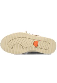 Suela de zapato beige con profundos surcos y patrón de chevrón, con un logo circular naranja marcado "Sorel" cerca del área del arco.