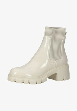 Botte chelsea en cuir laqué beige avec des panneaux latéraux en tissu côtelé, semelle texturée épaisse et tirette à l'arrière. Design élégant et moderne.