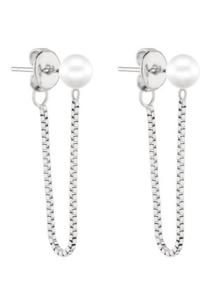 Hopeiset nappikorvakorut, joissa on pyöreät valkoiset helmet ja niihin kiinnitetyt hennot laatikkoketjurenkaat, jotka roikkuvat nappien alapuolella.