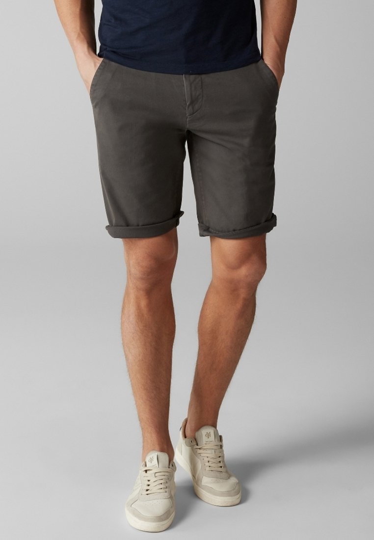 Shorts gris enroulés en tissu en mélange de coton, dotés de poches latérales et d'une taille plate, assortis à des baskets de couleur claire.