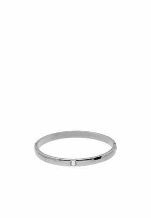Glad, gepolijst zilveren armband met een enkele kleine ronde heldere edelsteen in het midden, op een effen witte achtergrond.