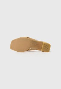 Pantof shoes bej cu tocul deschis, având o finisare din suede neted, cu un toc jos și o talpă din cauciuc inscripționată cu numele mărcii "paul green."