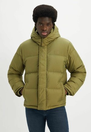 Chaqueta acolchada verde oliva con capucha, diseño acolchado y cierre frontal con cremallera. Incluye un pequeño parche con logo en el pecho.