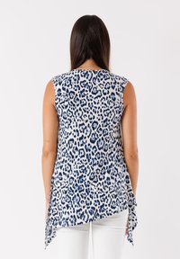 Top senza maniche di colore bianco con stampa leopardata blu, caratterizzato da un orlo asimmetrico e un tessuto morbido. Texture liscia e vestibilità comoda.