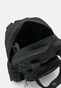 Mustmust mustrepp seljakott, millel on lukuga sulgemine, esikott ja kangas käepidemed. Siseosa näitab sileda voodriga ja väikese nähtava sildi.