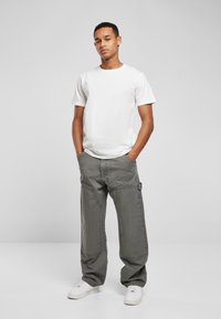 Hvit crewneck t-skjorte, grå løse cargo-bukser med sidelommer, og hvite joggesko. Jevn stoff, uformell design og avslappet passform.