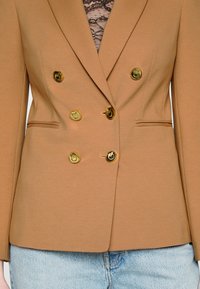 Blazer marron à double boutonnage en tissu lisse, doté de boutons dorés, d'un design ajusté et d'une coupe slim avec un col discret.