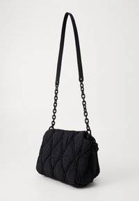 Schwarze, gesteppten Stofftasche mit einer Kettenriemen. Hat eine rechteckige Form, eine strukturierte Oberfläche mit diagonaler Naht und einen umklappbaren Deckel.