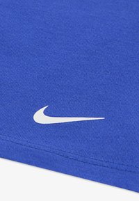 Blue fabric t-shirt with a textured surface featuring a white Nike logo design. The shirt has a round neckline and clean finishing edges.