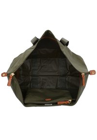 Borsa duffle verde oliva con un ampio interno con zipper. Presenta dettagli in pelle marrone, multiple tasche e una texture liscia. Comparto foderato incluso.