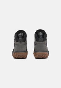 Czarno-szare buty trekkingowe z teksturowanym zamszowym wierzchem, gumową podeszwą z wyraźnym bieżnikiem i logo na pięcie.