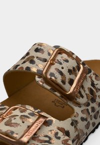 Sandales à imprimé léopard avec une base beige et des boucles en métal rose doré. Semelle en mousse et brides texturées douces pour un confort et un soutien optimaux.