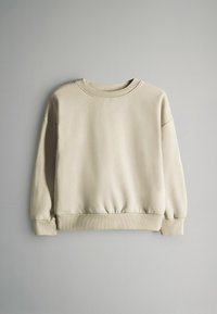 Béžová mikina z měkké látky. Má kulatý výstřih, žebrované manžety a pas. Má kleslá ramena pro pohodlný střih.