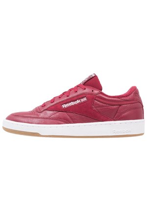 Czerwone skórzane sneakersy o teksturowanym wykończeniu, z białą gumową podeszwą środkową i gumową podeszwą zewnętrzną. Na boku i języku znajduje się logo Reebok.