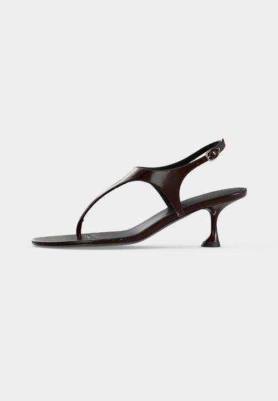 Σανδάλι slingback από σκούρο καφέ λουστρίνι με μικρό τακούνι και λουράκι ανάμεσα στα δάχτυλα σε λευκό φόντο.