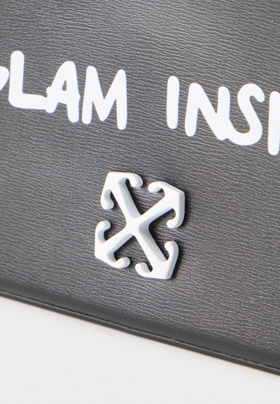 Μαύρη υφή επιφάνειας με λογότυπο λευκών στυλιζαρισμένων βελών και μερικό λευκό κείμενο με έντονα κεφαλαία γράμματα.