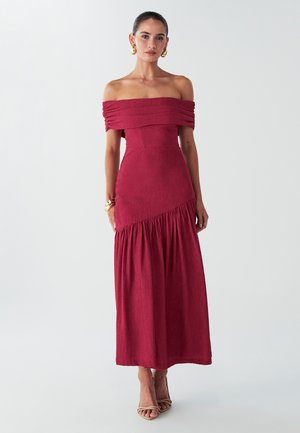Off-the-shoulder, burgundy maxi dress with textured fabric, fitted bodice, and gathered skirt detail. Simple, elegant design.