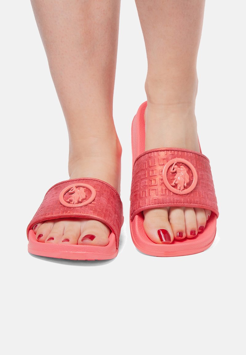 Korale klapki z gumy, z teksturowanym paskiem z okrągłym logo oraz wyprofilowaną podeszwą. Otwarty design z widocznymi palcami.