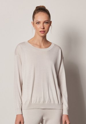 Light beige knit sweater with long sleeves, a round neckline, and a gathered hem. Soft texture and relaxed fit, suitable for casual wear.