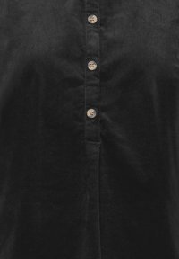 Devant d'une chemise en velours côtelé noire avec quatre boutons beiges en rangée verticale le long de la patte de boutonnage.