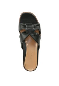 Sandale en cuir noir avec un design noué sur la bride. La semelle présente un contraste brun et une base lisse et plate.