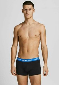 Schwarze Baumwoll-Boxershorts mit einem blauen elastischen Bund, der das "JACK & JONES"-Logo trägt; enganliegende Form und glatte Textur.