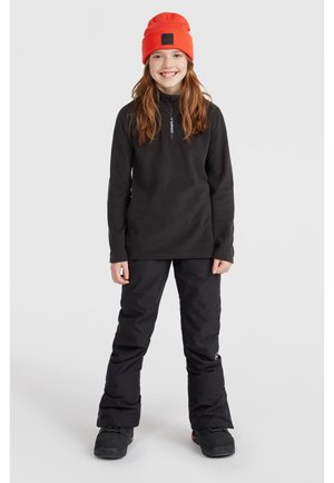 Pullover in pile nero con colletto con zip, abbinato a pantaloni da neve neri. Il modello indossa un berretto arancione acceso e stivali neri.